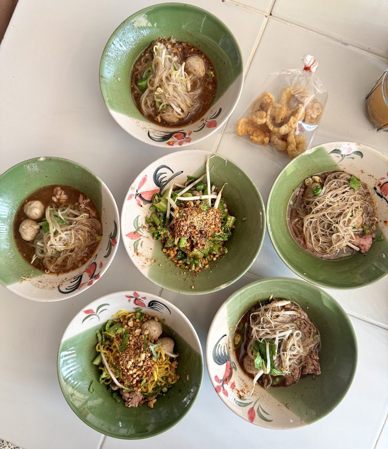 ก๋วยเตี๋ยวเรือห้าชามถ่ายจากด้านบน มีถุงกากหมูวางข้าง ๆ