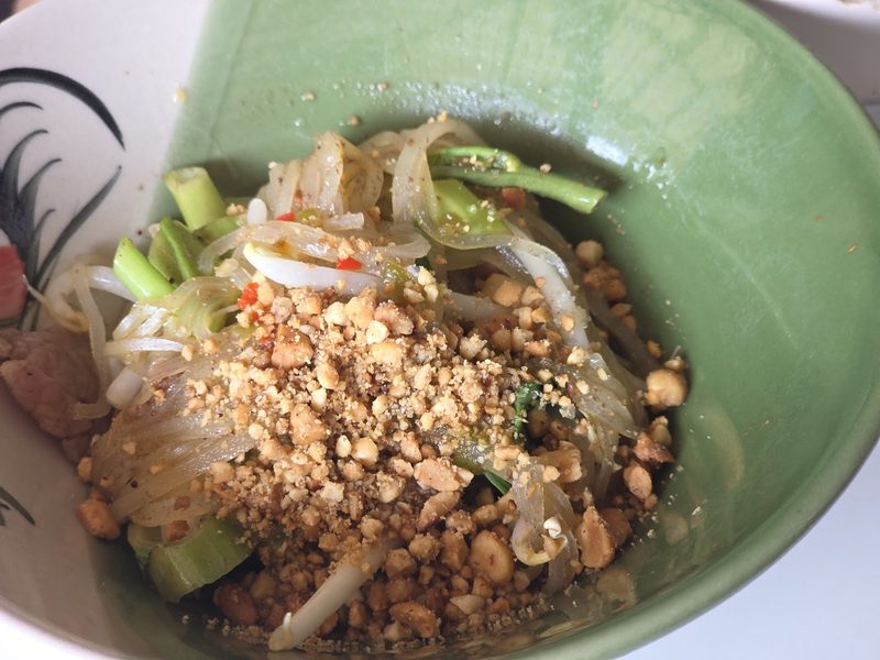 วุ้นเส้นแห้งโรยถั่วป่นและผักบุ้งในชามเขียว