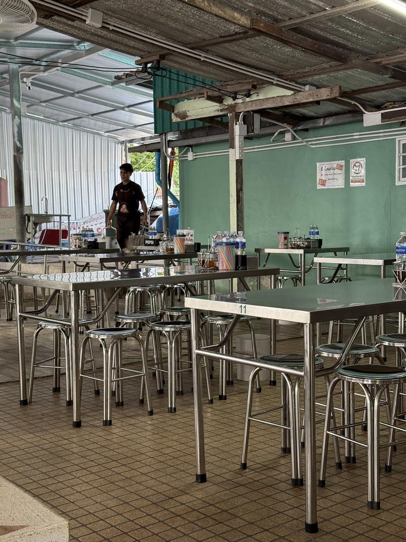 โต๊ะสเตนเลสเรียงรายในโถงร้าน ผนังสีเขียว
